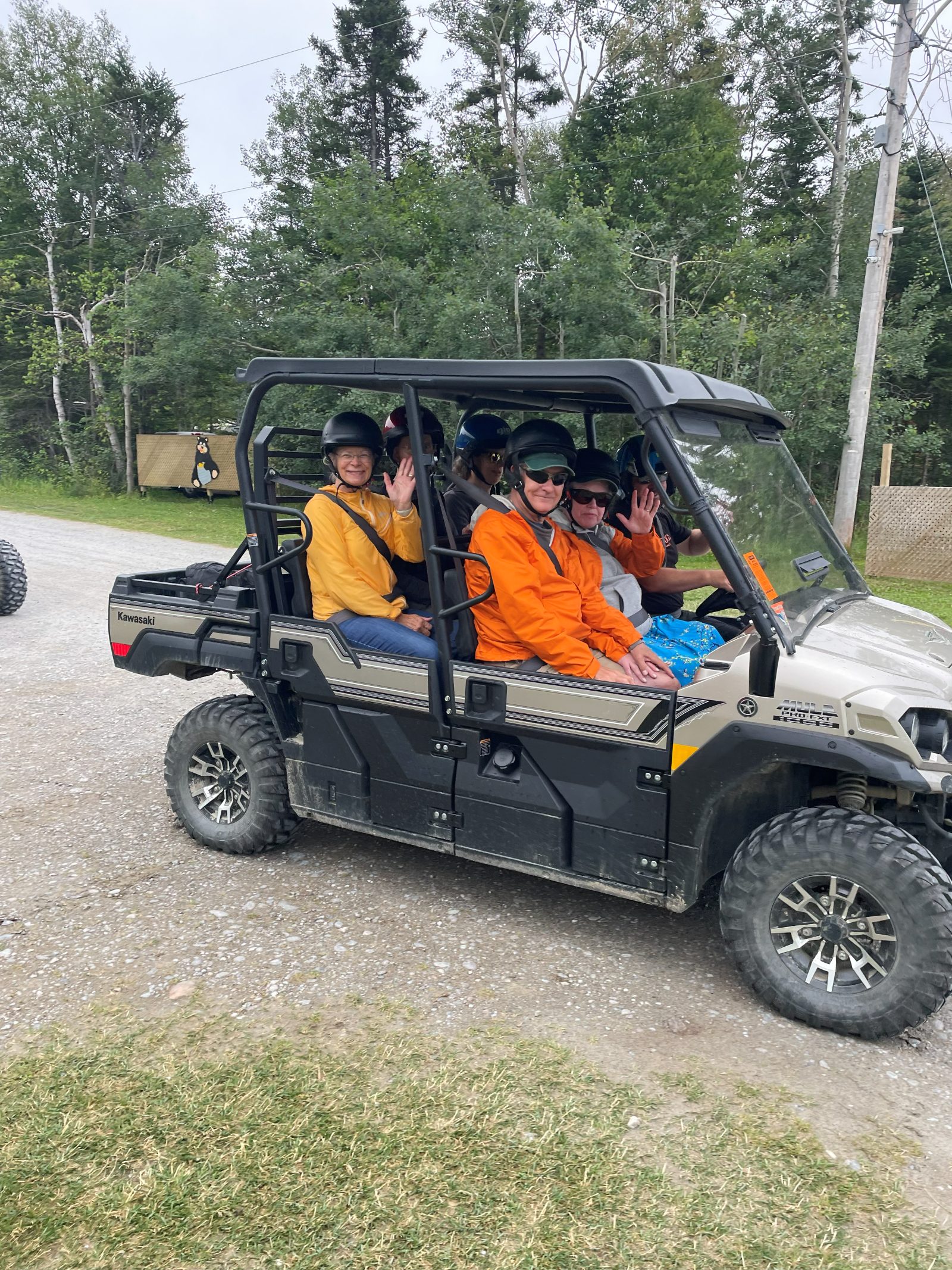 Travelers waving from a UTV on a gravel trail